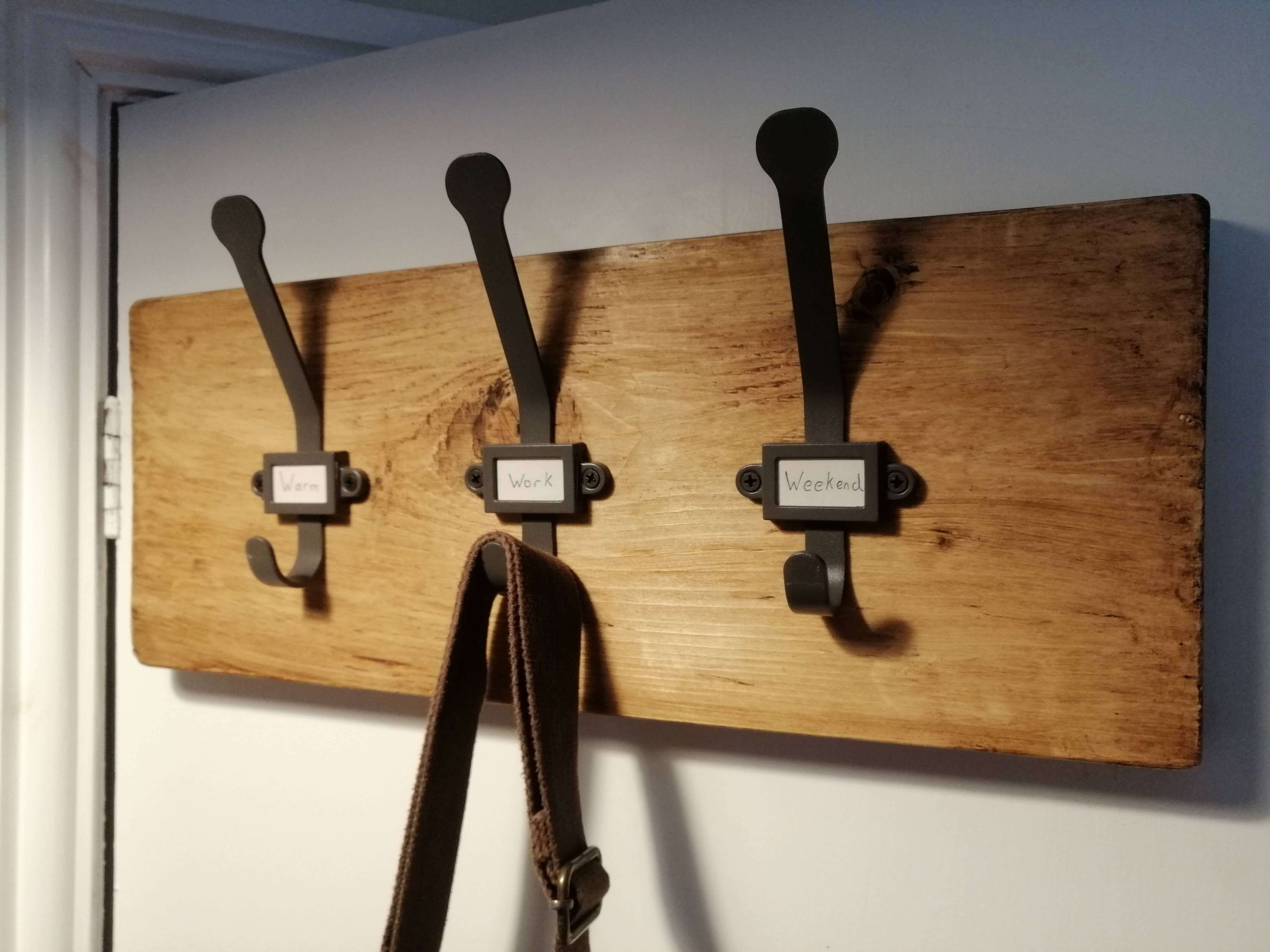 Rustic coat hooks with labels on a dark wooden backboad